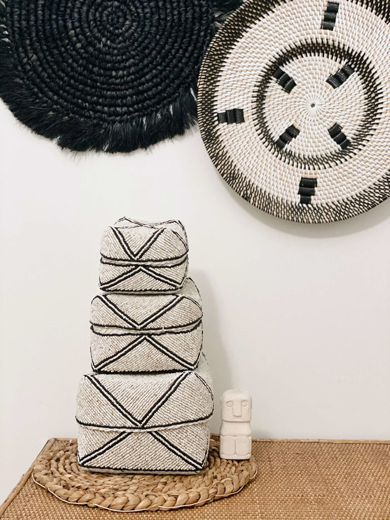 trio hand-beaded tan and black stripe bamboo basket on wooden table with decorative wall baskets