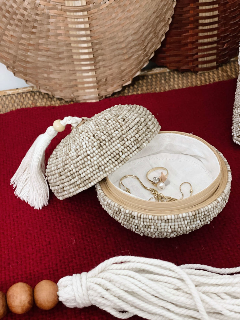 mini round hand-beaded tan bamboo basket with cream tassel on dresser holding gold jewelry