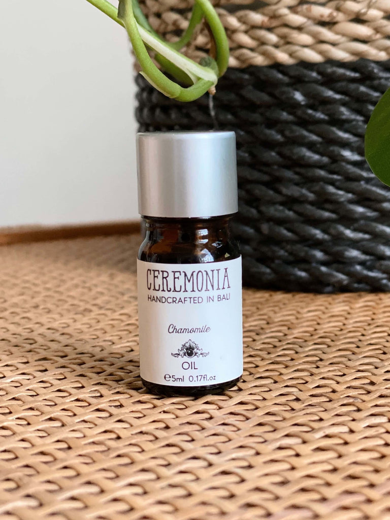 CEREMONIA chamomile essential oil in front of a black and brown woven plant pot on a wicker dresser