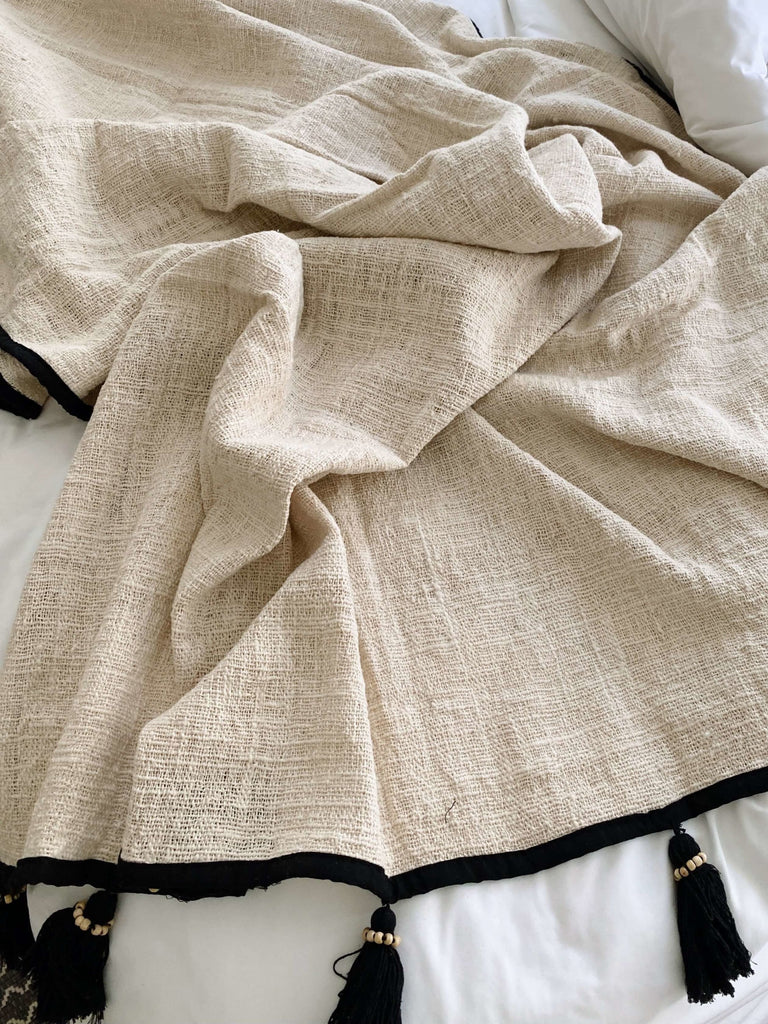 closeup of detail on cozy jute and linen throw blanket with black beaded macrame tassels