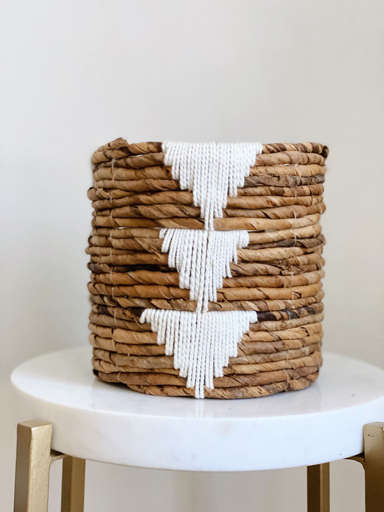 small brown handwoven banana leaf plant basket pot with white triangle design on white stool