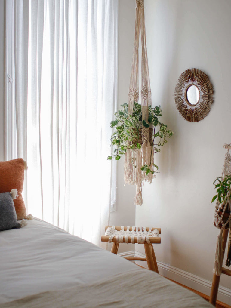 beautiful fringe macrame plant hanger with pothos plant next to papyrus motif mirror in earthy bohemian bedroom