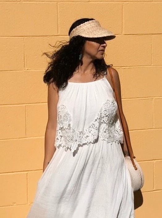 girl in bohemian fashion posing in front of a yellow brick wall wearing palm leaf natural sun visor on a sunny summer day