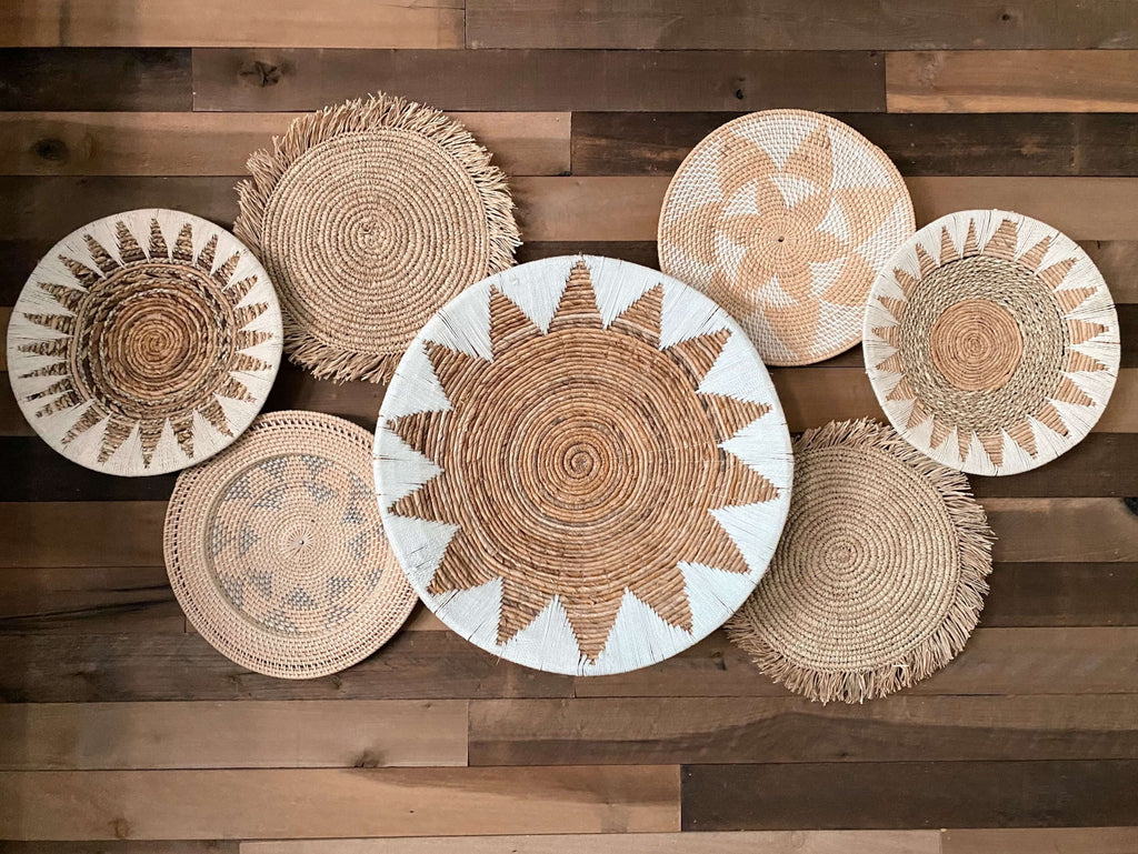 cluster of bohemian natural brown and white handwoven wall baskets on wooden surface