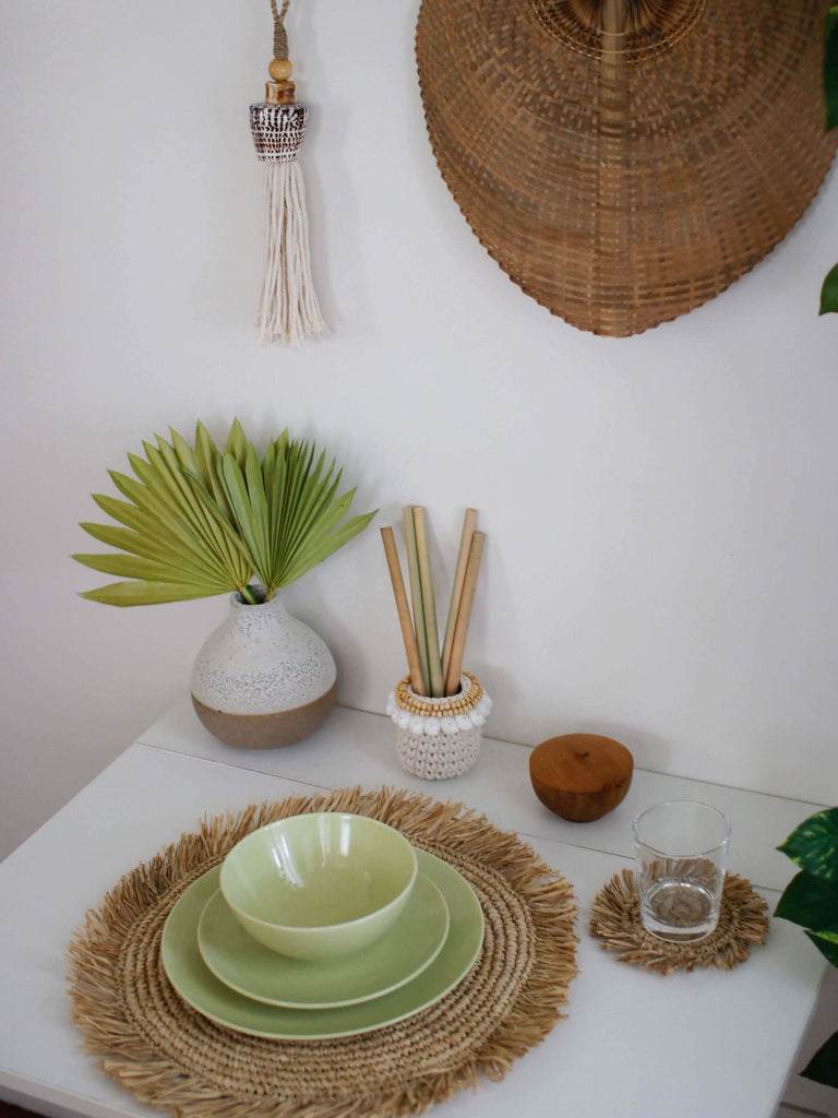 bohemian dining table setup with handmade reusable utensils and unique raffia fringe placemats