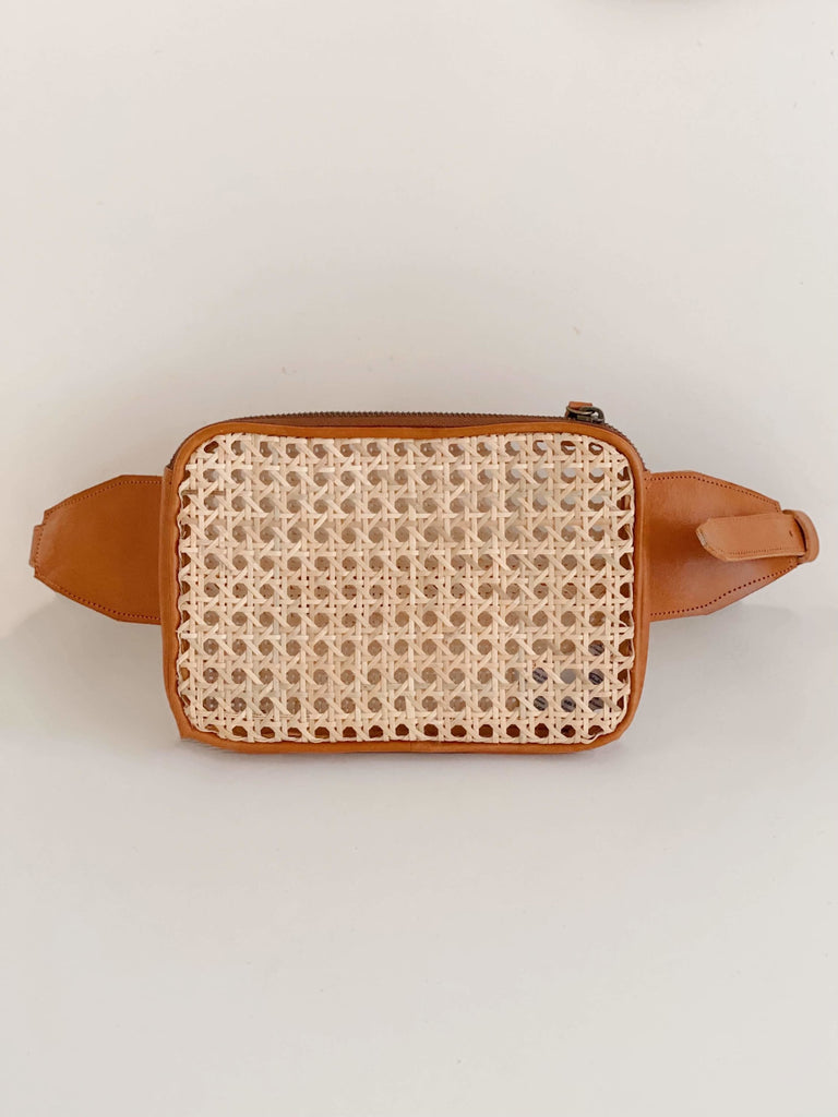product photo of detail on bohemian rattan and brown leather market fanny pack on white surface