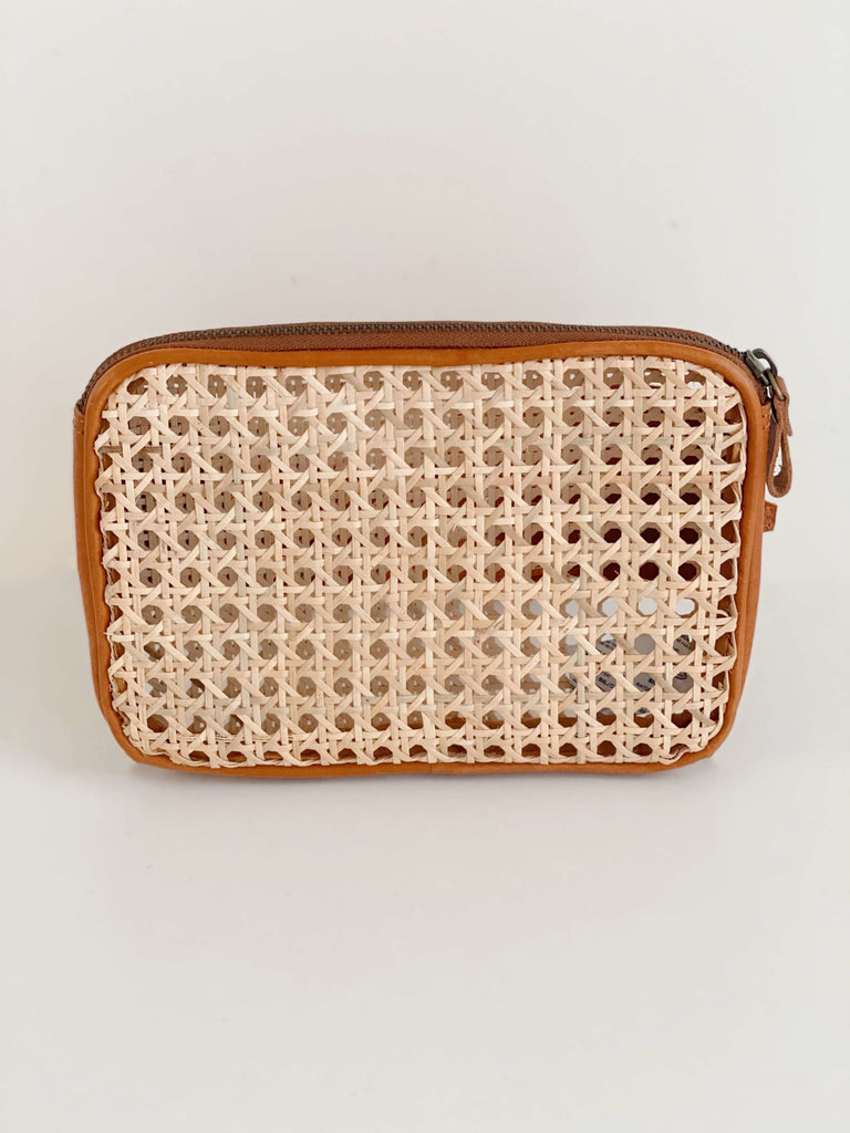 product photo of detail on bohemian rattan and brown leather market fanny pack on white surface