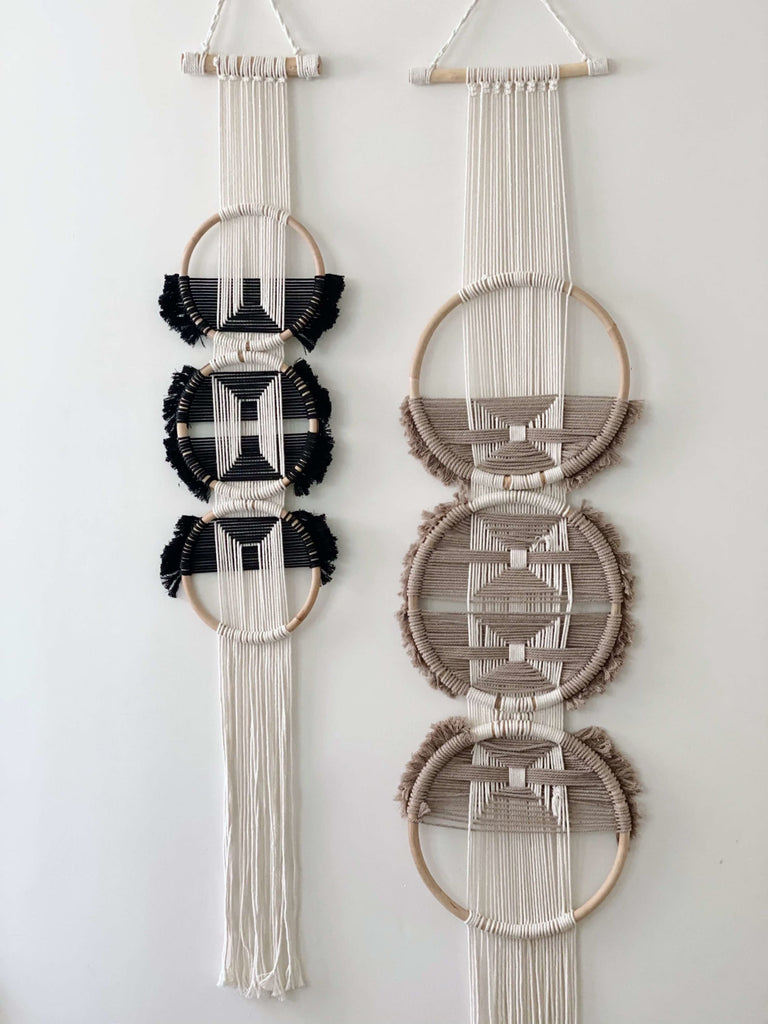two bohemian handmade three ring rattan black and mauve wall hanging tapestry on white wall