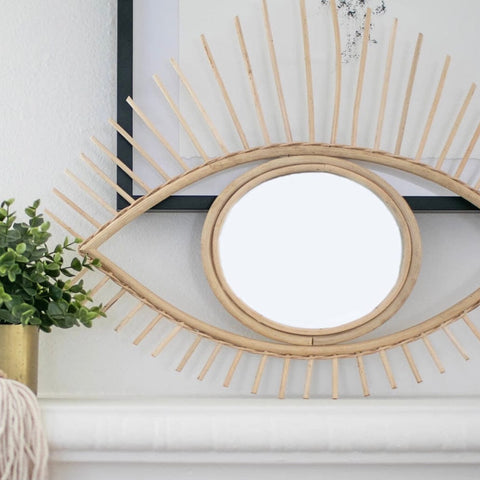 handmade rattan open eye mirror on mantel next to plant and boho decor