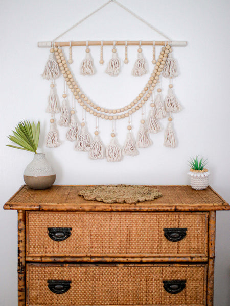 beautiful bohemian wall hanging macrame above a rattan and bamboo dresser