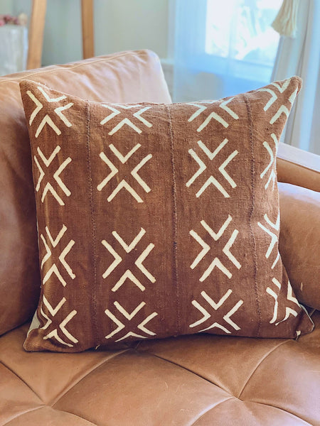 brown rust cross vintage african mudcloth decorative pillow on brown leather sofa