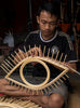 indonesian artisan crafting open eye rattan mirror inside workshop