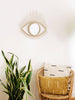 aesthetic rattan eye mirror in a boho modern room with wicker chair and vintage mudcloth throw pillows