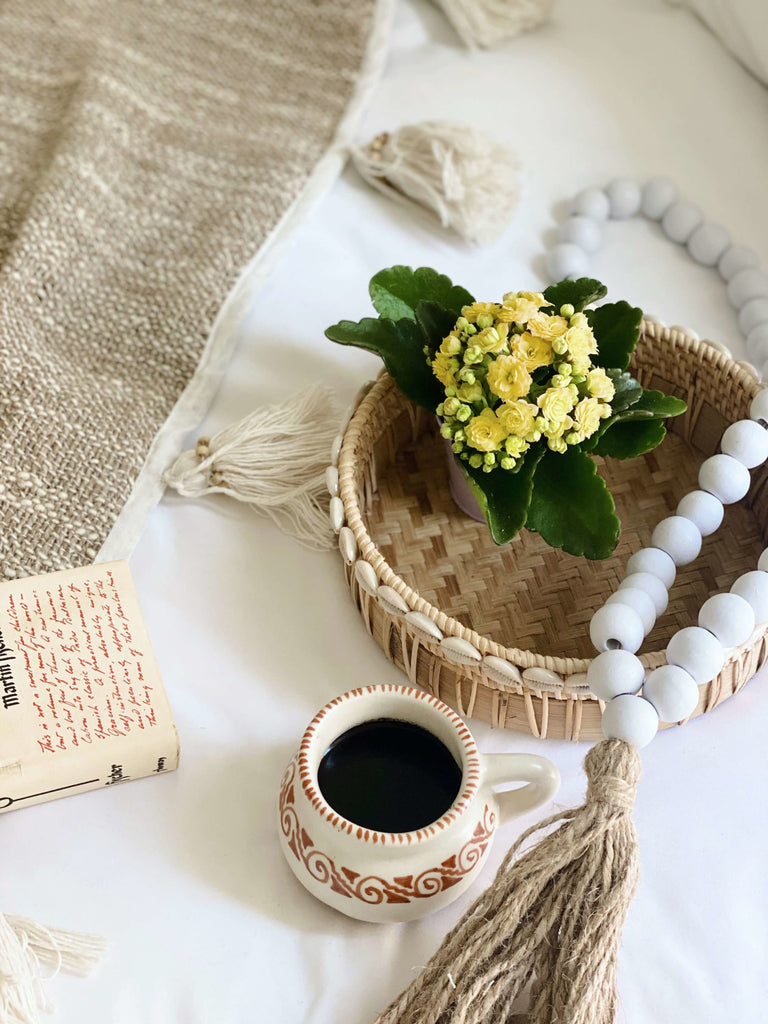 aerial shot of medium bamboo tray with cowrie shell detail surrounded by a high fire clay coffee mug and other bohemian decor