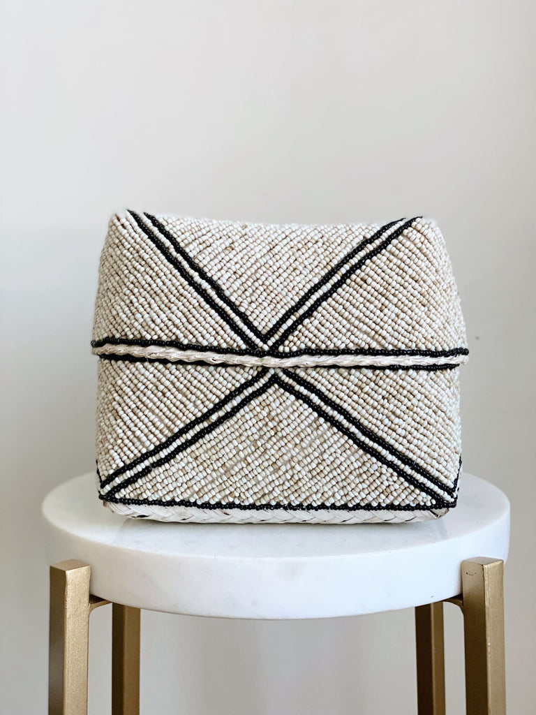 medium hand-beaded tan and black stripe bamboo basket on white marble stool
