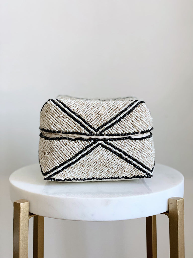 small hand-beaded tan and black stripe bamboo basket on white marble stool