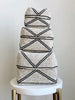set of three hand-beaded tan and black stripe bamboo baskets on a white marble stool