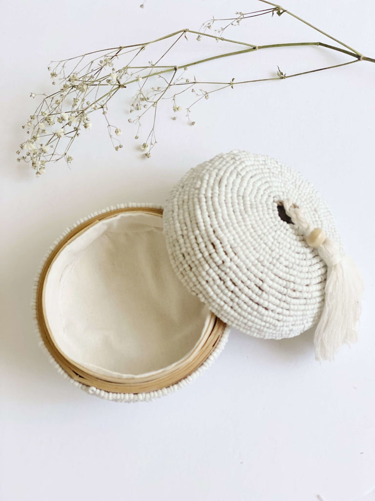 open mini round hand-beaded white bamboo basket with cream tassel on white background