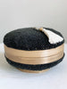 medium round hand-beaded black bamboo baskets with cream tassel on white table