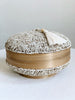 mini round hand-beaded tan bamboo basket with cream tassel on white table