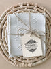 set of 4 waistloom embroidered coasters in cream colorway wrapped in twine
