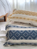 multiple handmade embroidered throw pillows piled on floor with light linens in the background
