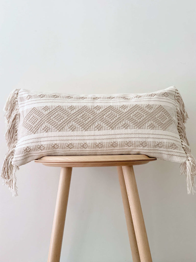 decorative embroidered taupe and cream cotton throw pillow on minimalist wooden stool