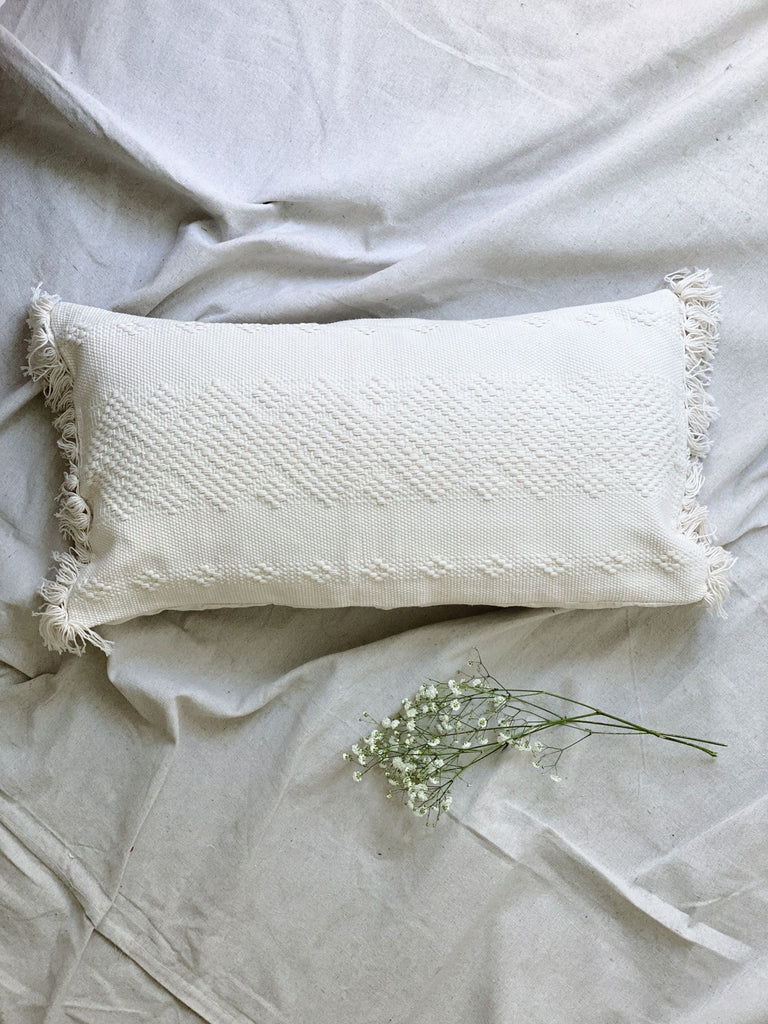 aesthetic photo of cream waistloom embroidered throw pillow on canvas next to baby's breath florals