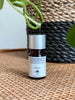 CEREMONIA jasmine essential oil in front of a black and brown woven plant pot on a wicker dresser