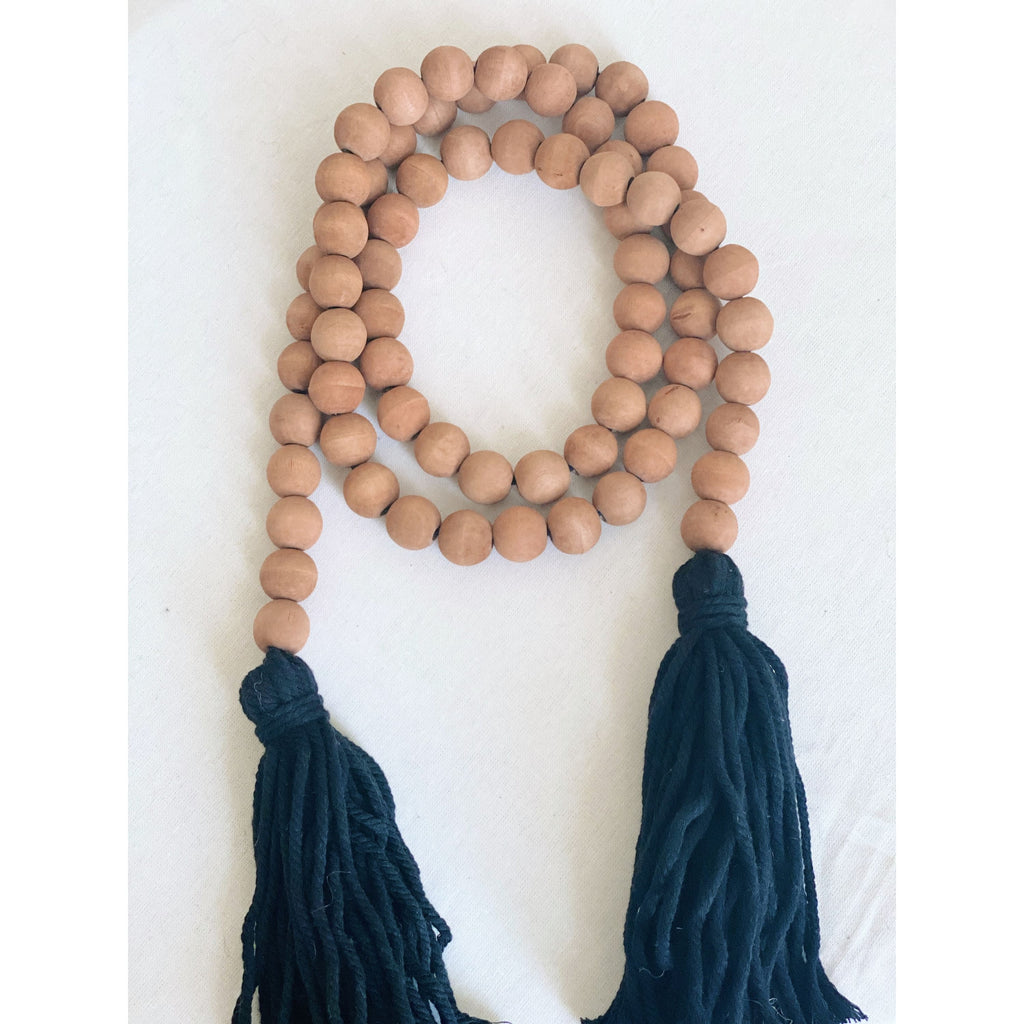 brown wooden bead garland with black tassels laid on a white surface