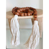 brown wooden bead garland with cream tassels on a wooden stool