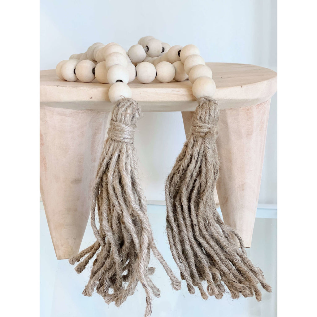 natural cream wooden bead garland with brown jute tassel on wooden stool