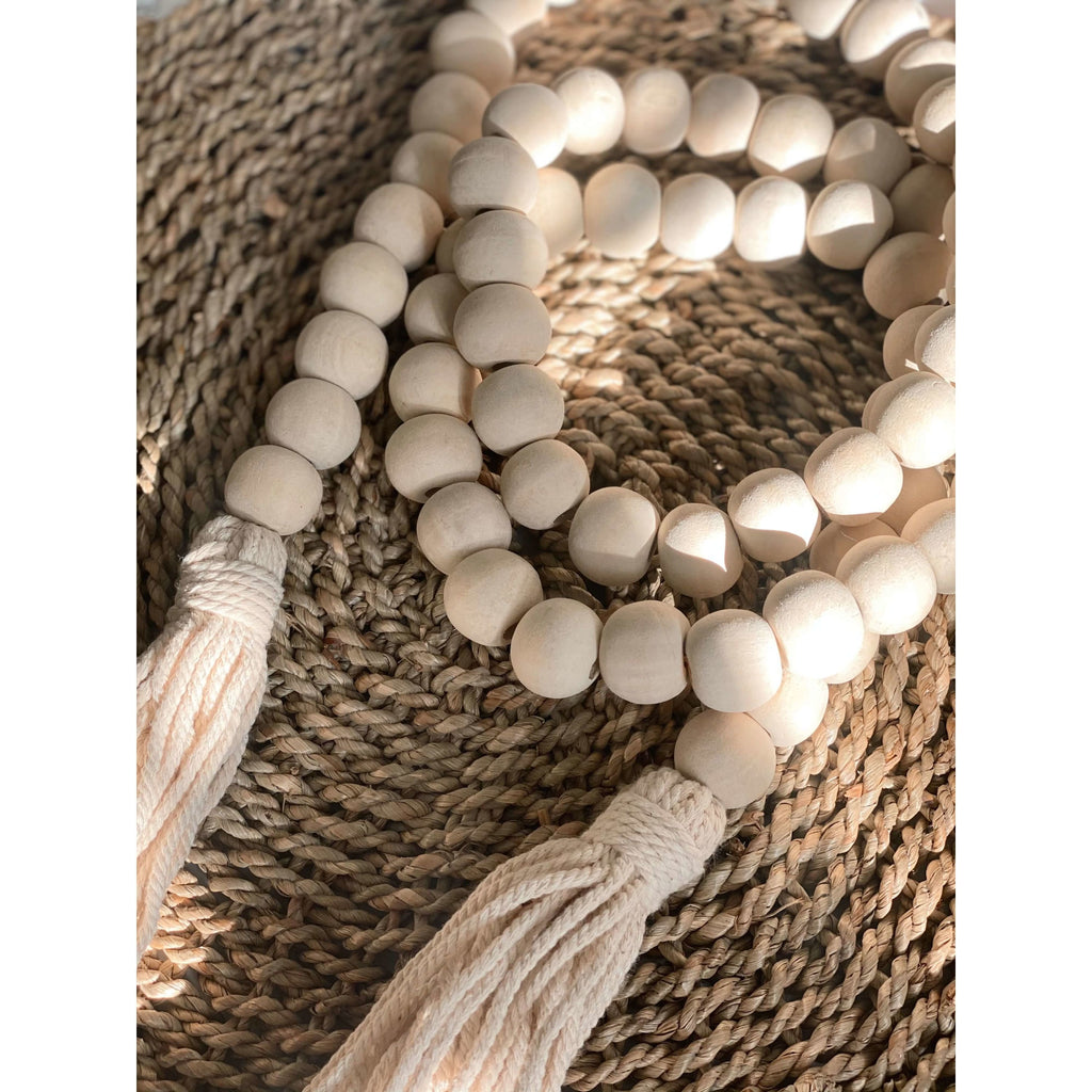 bohemian natural wooden bead garland with cream tassels on a woven wicker surface