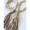boho natural wooden bead garland with brown jute tassels laid on a white surface creating a heart shape