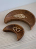close-up of set of two handcarved crescent moon teak wood dishes holding dainty feminine jewelry