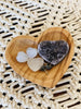 mini hand-carved heart teak dish with heart-shaped crystals and a pair of earrings on macrame surface