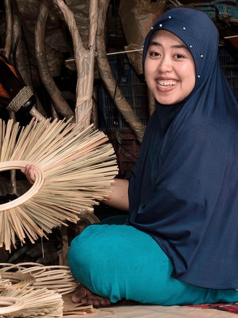 smiling artisan holding handmade straw fiber mirror