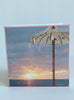 stationary card with a close-up of a large beach umbrella and a background of a sunset at the beach