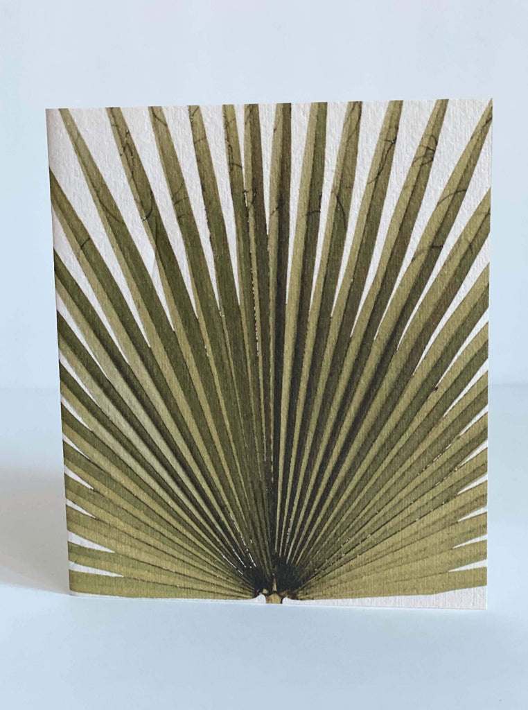 white stationary card with a print of a large green palm leaf