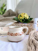 beautiful high fire clay white mug with brown tribal design on bed with other boho chic decor
