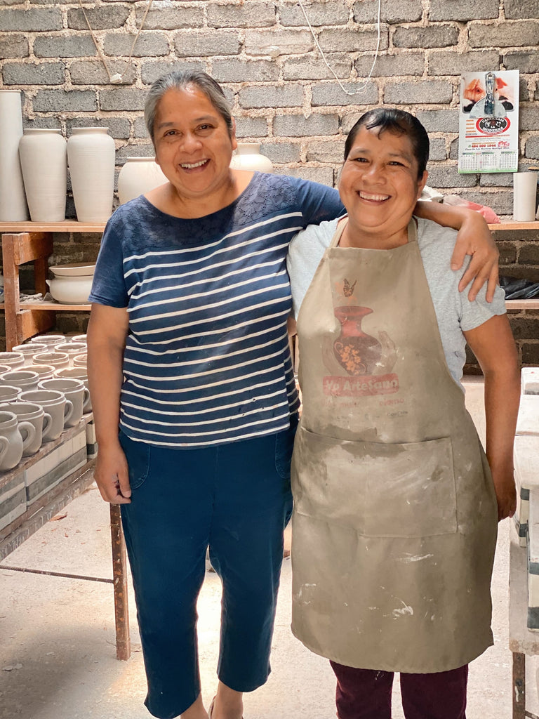 two happy smiling artisans standing proudly at their pottery workshop
