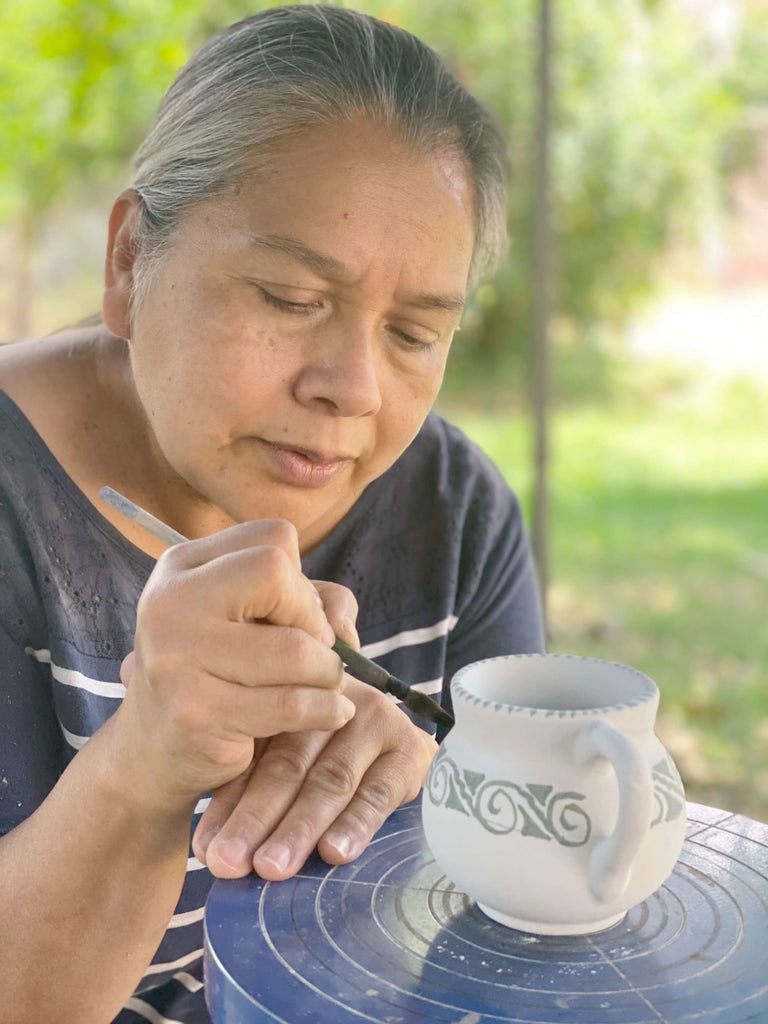 master artisan maker hand-painting indigenous tribal design on high fire clay stoneware mug