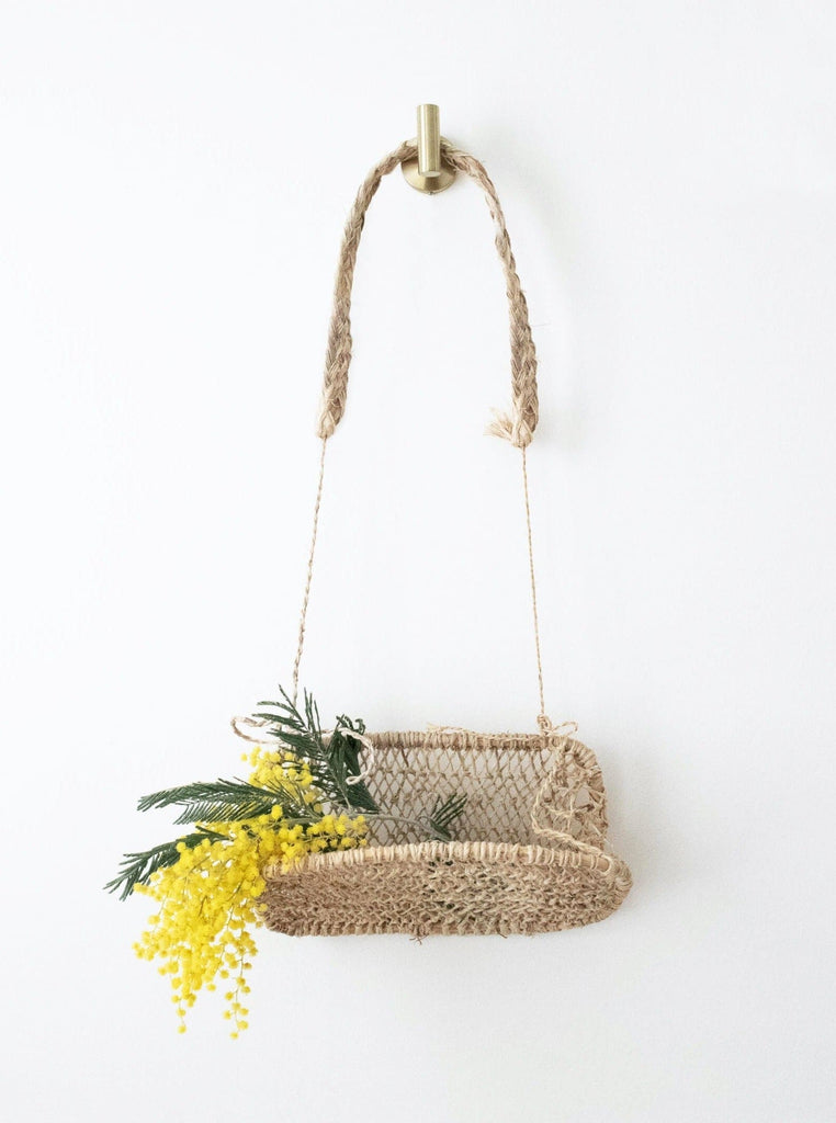 cottagecore handwoven hanging wall basket with beautiful yellow flowers hanging on white wall