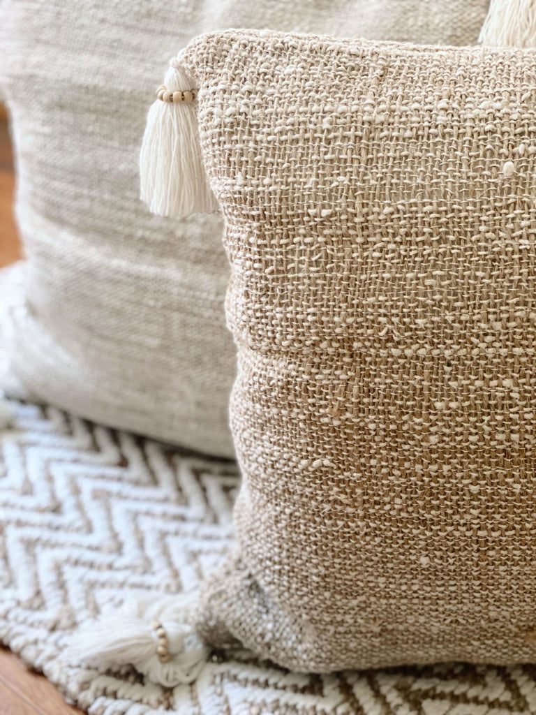 closeup of detail on bohemian handwoven jute and linen pillow cover with cream tassels