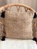 decorative bohemian handwoven jute throw pillow with black tassels for scandi boho decor on wicker chair