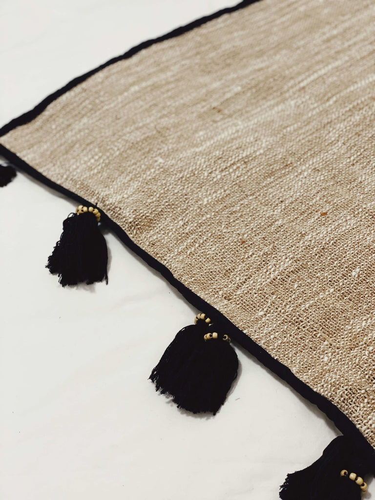closeup of detail on cozy jute and linen throw blanket with black beaded macrame tassels