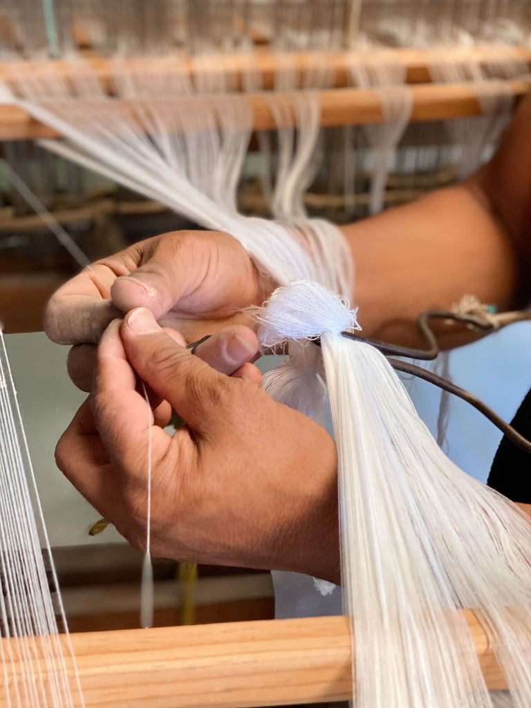 close up of artisan hands weaving threads to make CEREMONIA white linen napkins