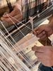 close up of two artisans working together to weave threads to make CEREMONIA white linen napkins