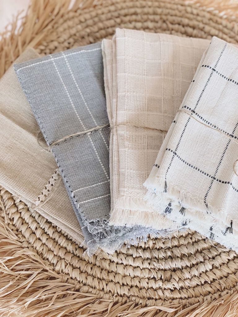 set of four different stunning detailed handwoven natural linen napkins folded neatly on bohemian fringe coaster
