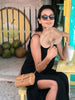 girl in bohemian cafe cooling off with handwoven palm leaf fan and coconut shake